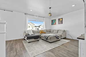 Living room with light wood-type flooring, a textured ceiling, baseboards, and recessed lighting