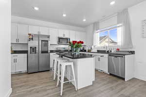 Kitchen featuring appliances with stainless steel finishes, a kitchen island, and white cabinetry