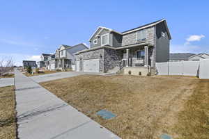 View of front of property featuring a residential view, stone siding, fence, and driveway