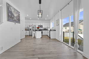 Kitchen with dark countertops, a kitchen island, hanging light fixtures, stainless steel appliances, and white cabinetry