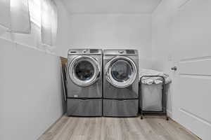 Laundry room with washer and dryer, laundry area, and light wood finished floors