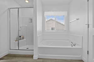 Full bath featuring a bath, a shower stall, and wood finished floors