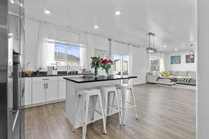 Kitchen with dark countertops, open floor plan, white cabinets, a kitchen island, and a kitchen bar