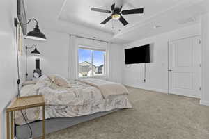 Bedroom featuring baseboards, visible vents, a raised ceiling, ceiling fan, and carpet flooring