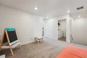 Interior space featuring carpet flooring, washing machine and clothes dryer, baseboards, visible vents, and recessed lighting