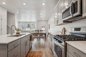 Kitchen featuring gray cabinetry, light countertops, appliances with stainless steel finishes, and a sink