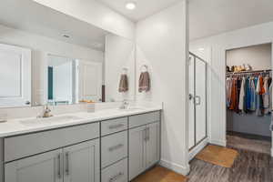 Full bath featuring a stall shower, visible vents, wood finished floors, and a sink