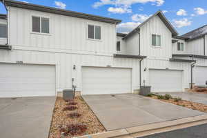 View of front of property featuring a garage, board and batten siding, and central AC unit