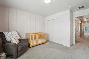 Carpeted bedroom featuring a closet, a decorative wall, visible vents, and attic access