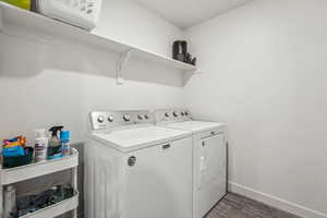 Laundry room with washing machine and clothes dryer, baseboards, laundry area, and dark wood finished floors