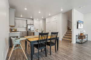 Dining area with a textured ceiling, baseboards, wood finished floors, recessed lighting, and stairway