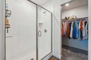 Bathroom with a spacious closet, recessed lighting, baseboards, and a shower stall