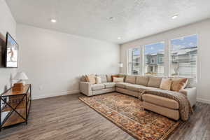 Living area featuring dark wood-type flooring, baseboards, and recessed lighting