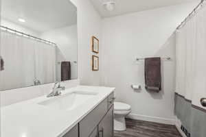 Bathroom featuring visible vents, baseboards, toilet, wood finished floors, and vanity