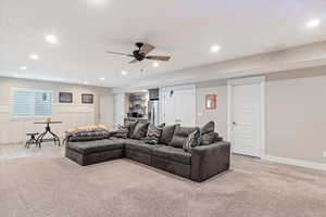 Living room with wainscoting, light wood-style flooring, a ceiling fan, and recessed lighting