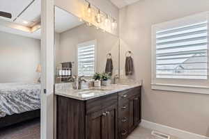 Ensuite bathroom with double vanity, baseboards, visible vents, ensuite bath, and a sink