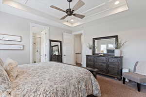 Bedroom with ceiling fan, ensuite bathroom, a tray ceiling, dark colored carpet, and recessed lighting