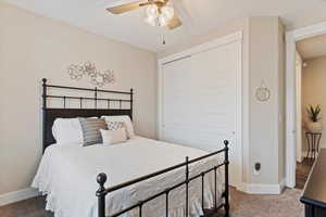 Carpeted bedroom with a closet, a ceiling fan, and baseboards