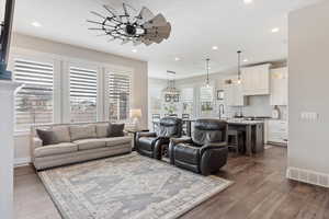 Living room featuring dark wood-style floors, ceiling fan, baseboards, and recessed lighting