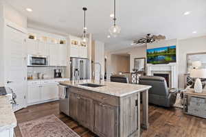 Kitchen with a center island with sink, high end appliances, glass insert cabinets, white cabinetry, and a sink