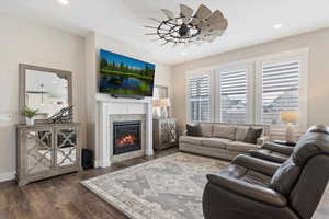 Living room featuring a ceiling fan, a glass covered fireplace, recessed lighting, and wood finished floors