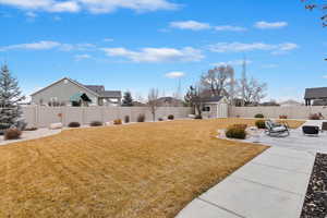 View of yard featuring an outbuilding, a patio, a fenced backyard, a storage shed, and a residential view