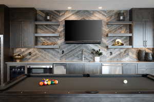 Interior space with dishwasher, billiards, backsplash, and a sink