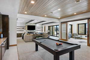 Rec room with a stone fireplace, recessed lighting, light carpet, wood ceiling, and baseboards