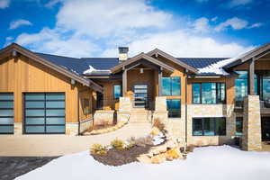 View of front of home with a garage, stone siding, metal roof, and a standing seam roof