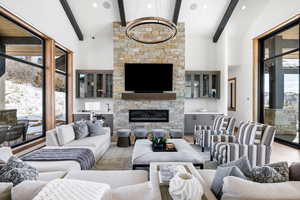 Living area with high vaulted ceiling, beam ceiling, light wood-style floors, and a stone fireplace