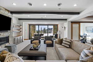 Living room featuring carpet, beam ceiling, a fireplace, visible vents, and baseboards