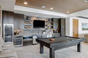 Rec room with beverage cooler, wooden ceiling, a raised ceiling, and wet bar