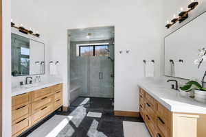 Bathroom with a sink, two vanities, a shower stall, and baseboards