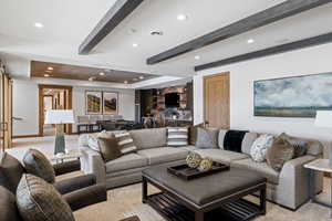 Living room with a barn door, recessed lighting, visible vents, baseboards, and beamed ceiling