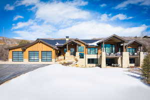 View of front of house with metal roof, stone siding, a chimney, and a standing seam roof