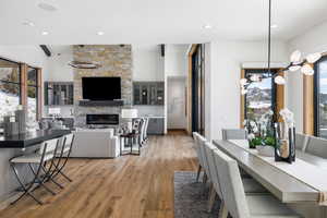 Dining area with light wood-style flooring, a wealth of natural light, a stone fireplace, and recessed lighting