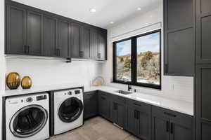 Laundry area with light tile patterned flooring, recessed lighting, separate washer and dryer, a sink, and cabinet space