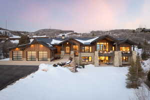 View of front of home with a balcony, a standing seam roof, stone siding, and aphalt driveway