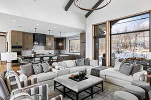 Living room with high vaulted ceiling, wood finished floors, beam ceiling, and recessed lighting