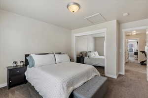 Bedroom featuring attic access, a closet, dark carpet, and baseboards