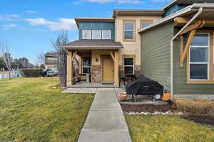 View of front of property featuring a front yard, stone siding, a patio, and stucco siding