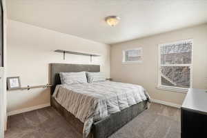 Carpeted bedroom featuring a textured ceiling and baseboards