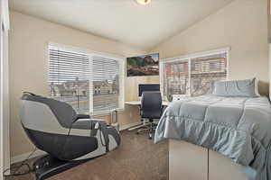 Bedroom featuring vaulted ceiling, carpet flooring, and baseboards