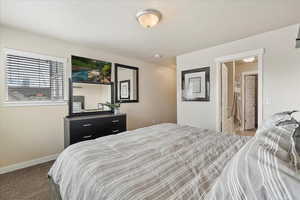 Bedroom with carpet, baseboards, and a textured ceiling