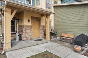 Doorway to property featuring stone siding, a patio, and stucco siding