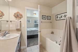 Bathroom with a garden tub, connected bathroom, vanity, baseboards, and tile patterned floors