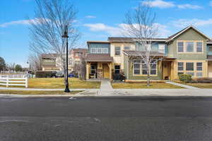 View of front facade with stone siding, a front yard, and fence