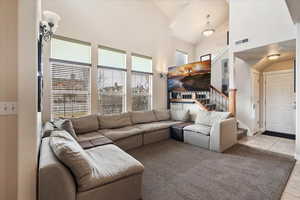 Living room with stairway, visible vents, high vaulted ceiling, and light tile patterned flooring