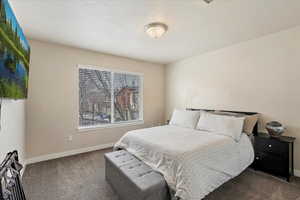 Carpeted bedroom featuring a textured ceiling and baseboards