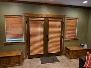 Foyer featuring light tile patterned floors, baseboards, and crown molding